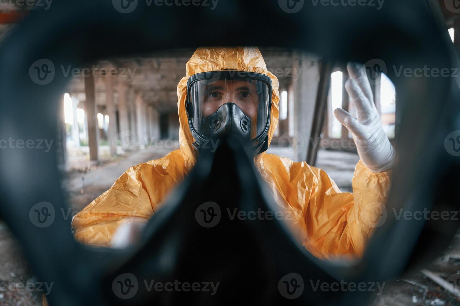 First person view ,through respirator. Man dressed in chemical protection suit in the ruins of the post apocalyptic building photo