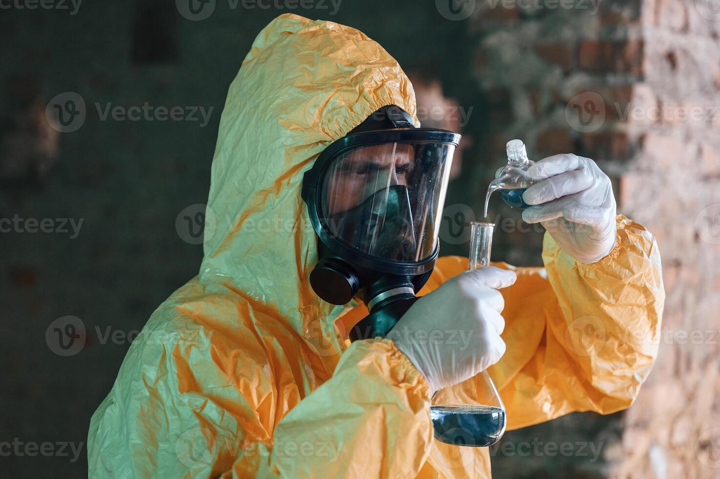 Examining, radioactive liquid. Man dressed in chemical protection suit in the ruins of the post apocalyptic building photo