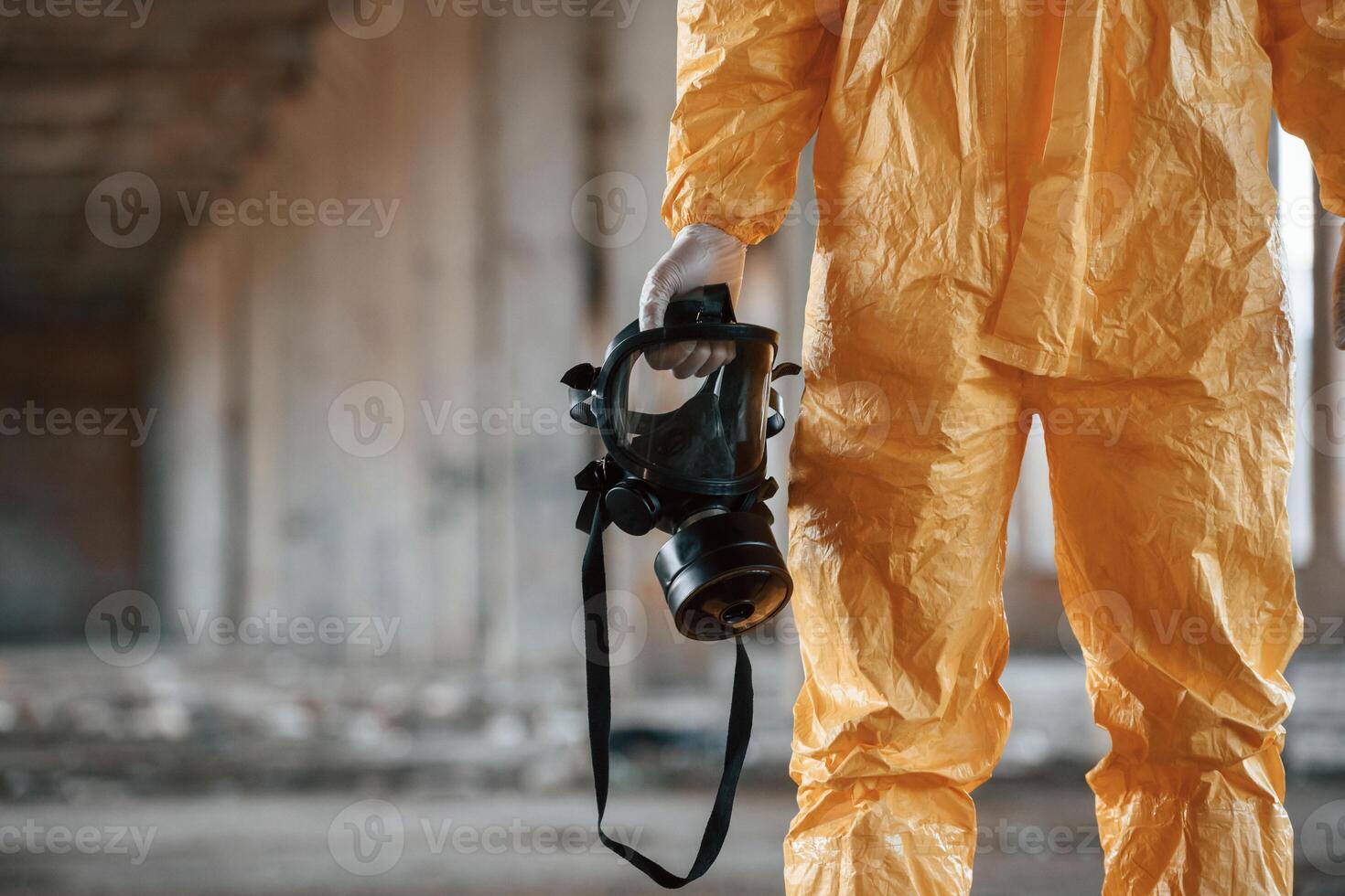 Holding gas, mask. Man dressed in chemical protection suit in the ruins of the post apocalyptic building photo