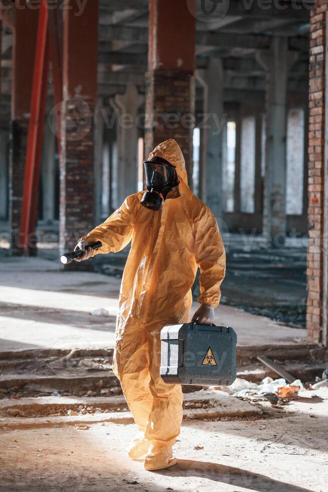 Man dressed in, chemical protection suit in the ruins of the post apocalyptic building photo