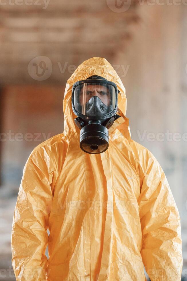 Portrait, of man dressed in chemical protection suit that is in the ruins of the post apocalyptic building photo