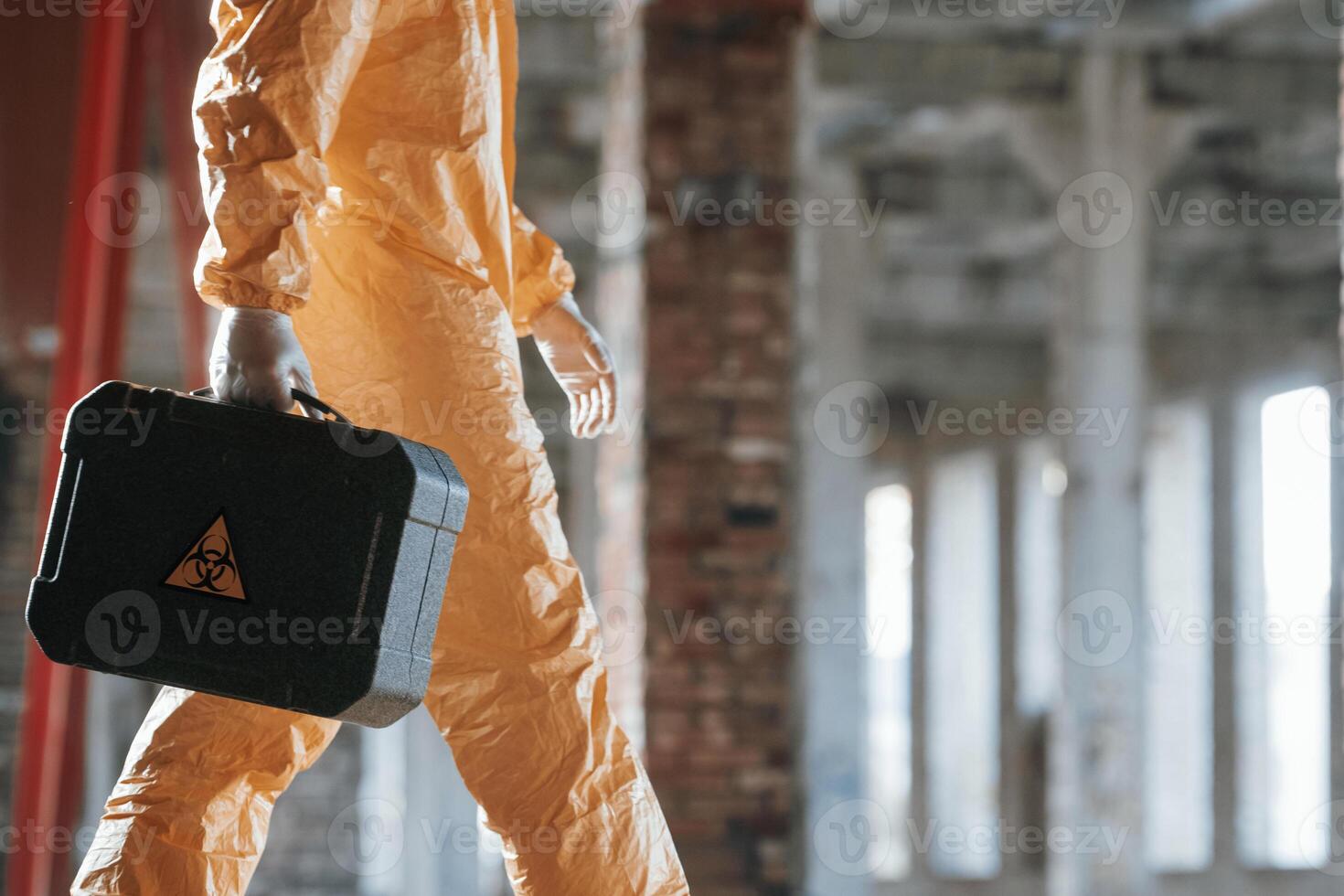 The ,case with biohazard sign on it. Man dressed in chemical protection suit in the ruins of the post apocalyptic building photo