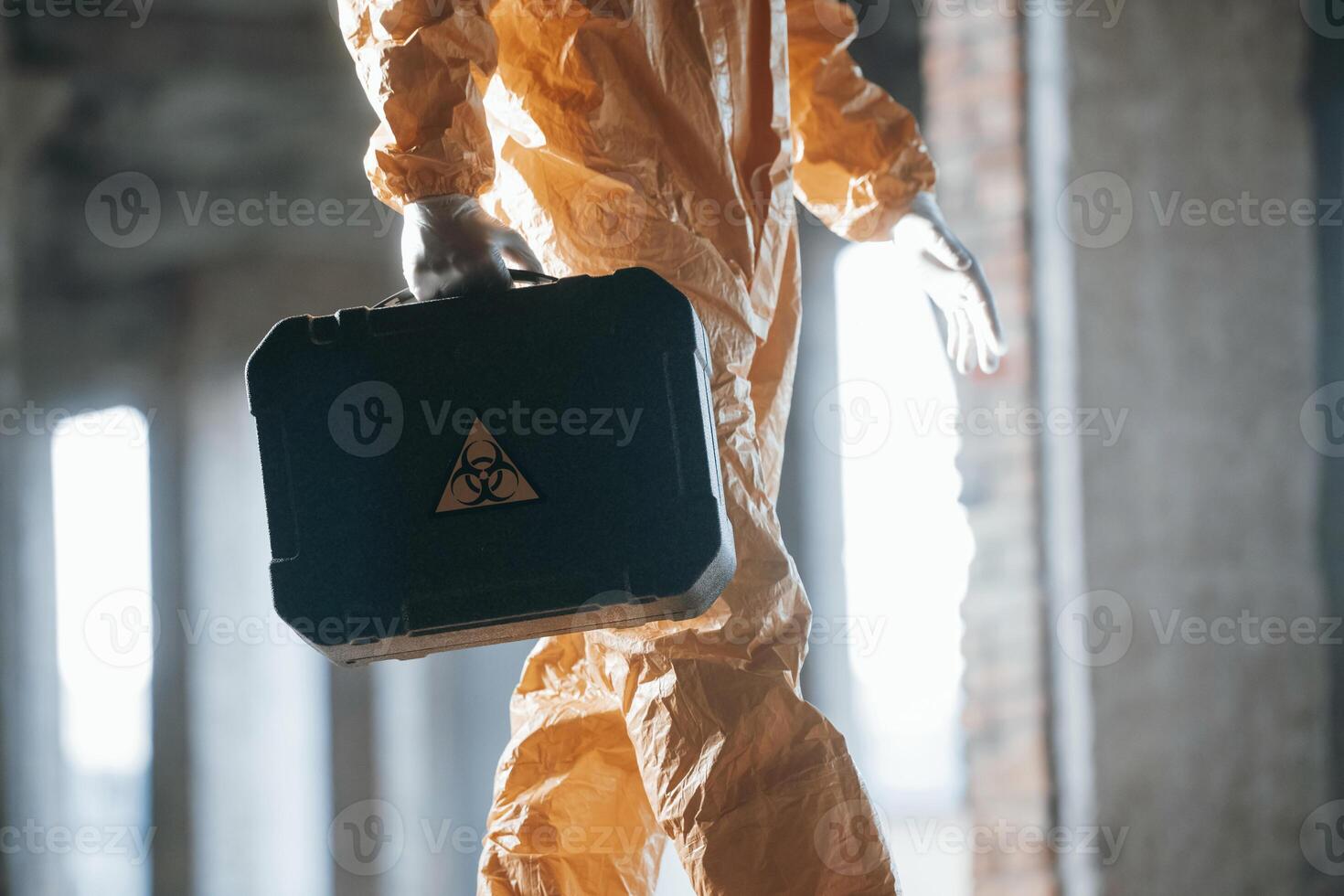The case ,with, biohazard sign on it.. Man dressed in chemical protection suit in the ruins of the post apocalyptic building photo
