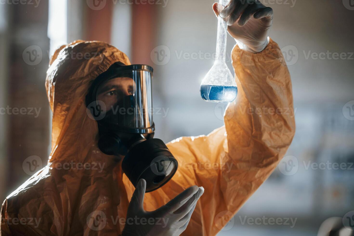 Examining ,radioactive liquid. Man dressed in chemical protection suit in the ruins of the post apocalyptic building photo