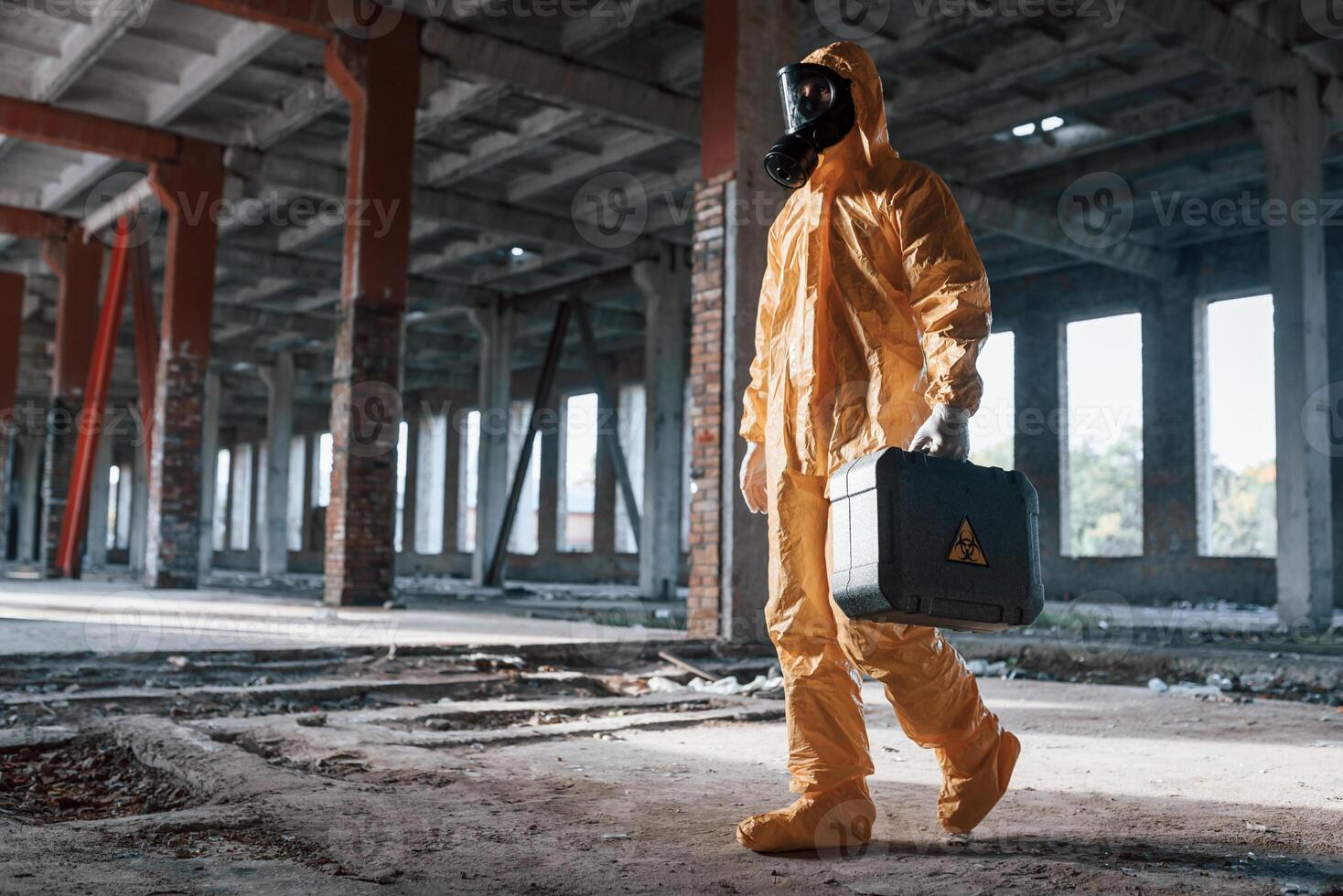 View from the ,side. Man dressed in chemical protection suit in the ruins of the post apocalyptic building photo