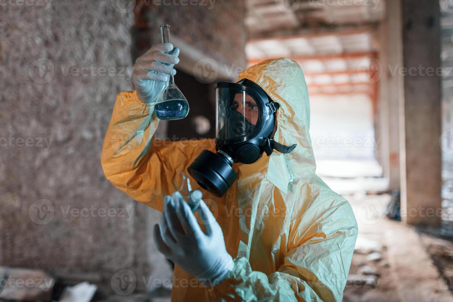 A test tube with radioactive ,materials. Man dressed in chemical protection suit in the ruins of the post apocalyptic building photo