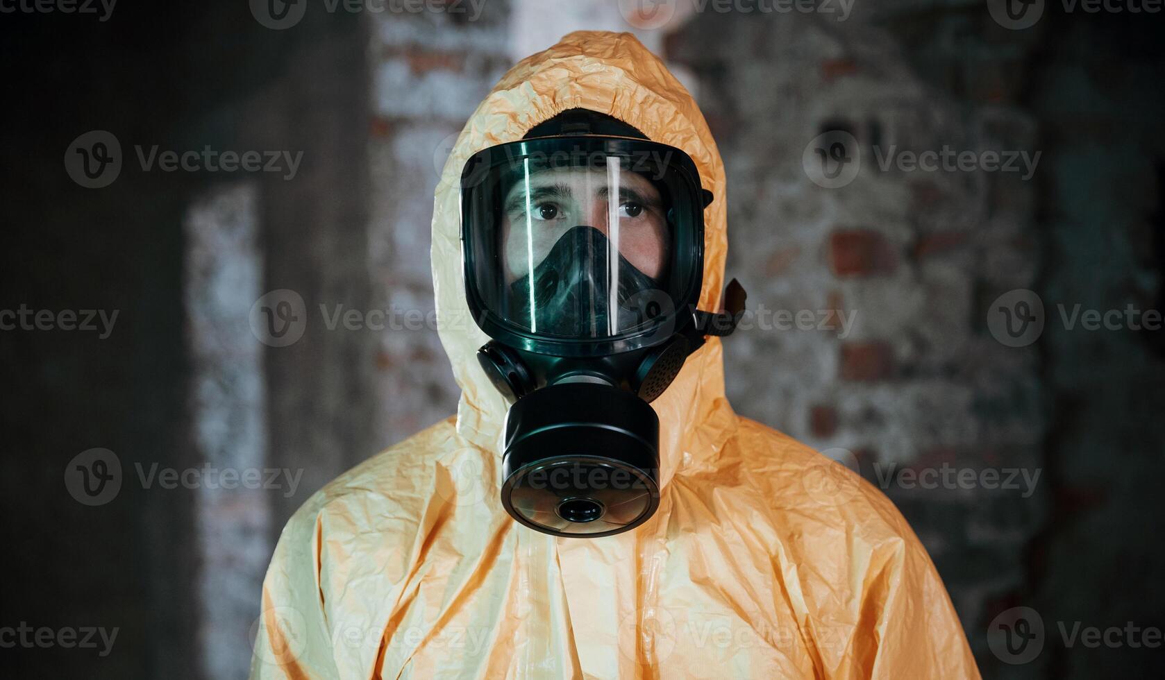 In respirator, portrait. Man dressed in chemical protection suit in the ruins of the post apocalyptic building photo