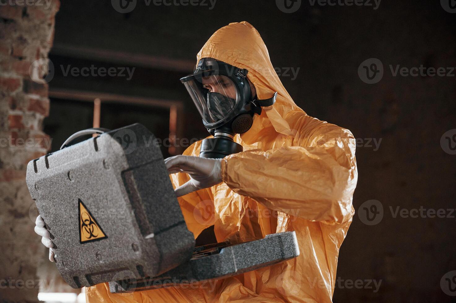 Sitting ,with radioactive case. Man dressed in chemical protection suit in the ruins of the post apocalyptic building photo