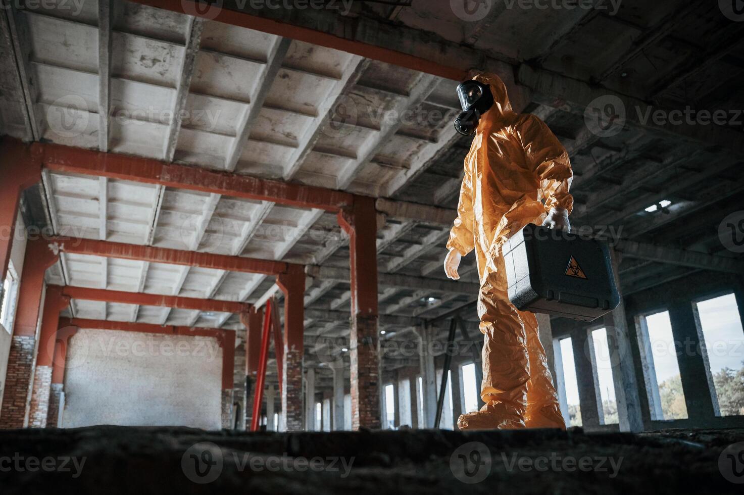 View from below. Man dressed i,n chemical protection suit in the ruins of the post apocalyptic building photo