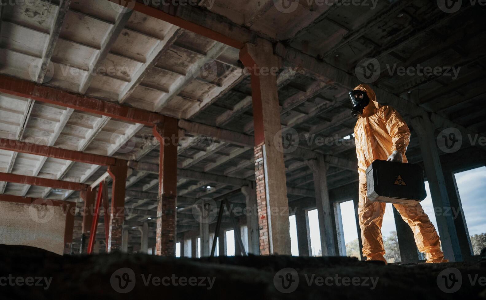 View from ,below. Man dressed in chemical protection suit in the ruins of the post apocalyptic building photo