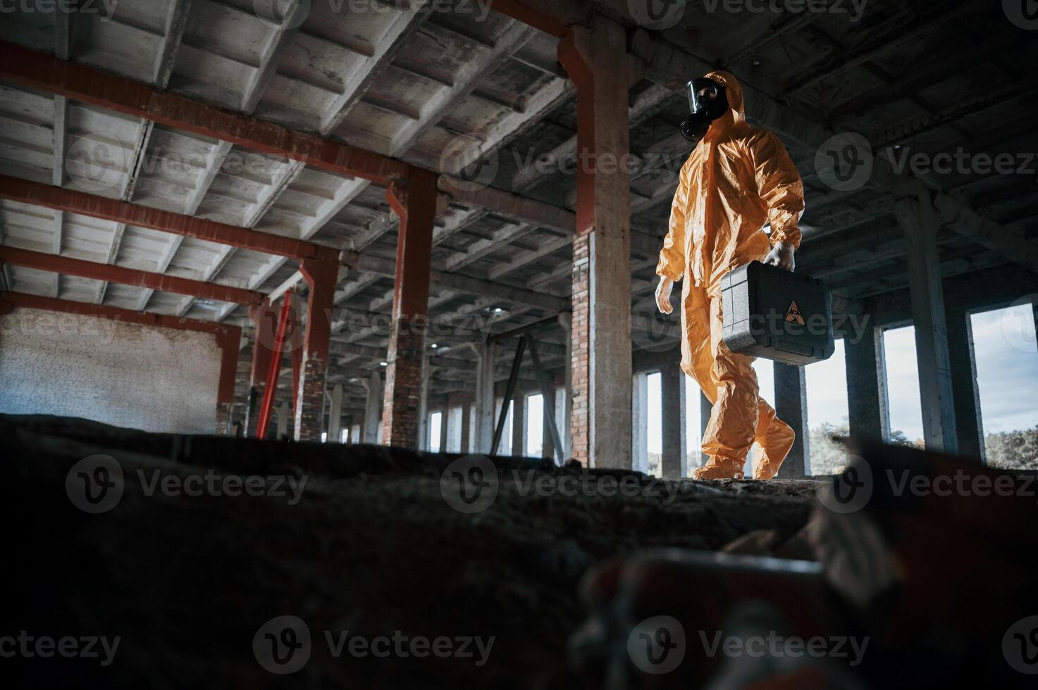 View from below. Man, dressed in chemical protection suit in the ruins of the post apocalyptic building photo