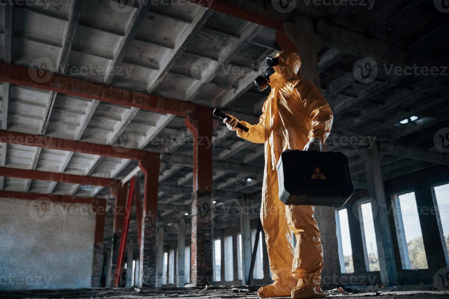 Indoors with flashlight. Man ,dressed in chemical protection suit in the ruins of the post apocalyptic building photo