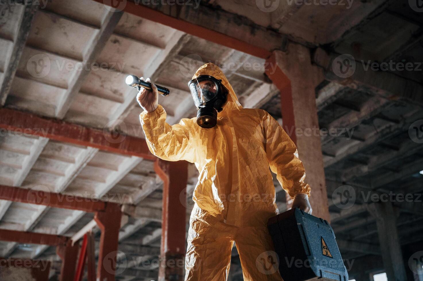 Indoors with, flashlight. Man dressed in chemical protection suit in the ruins of the post apocalyptic building photo