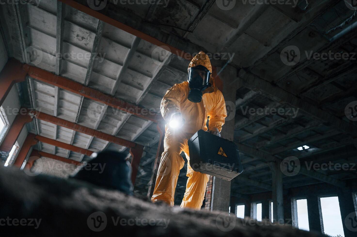 Looking below at the object. Man ,dressed in chemical protection suit in the ruins of the post apocalyptic building photo