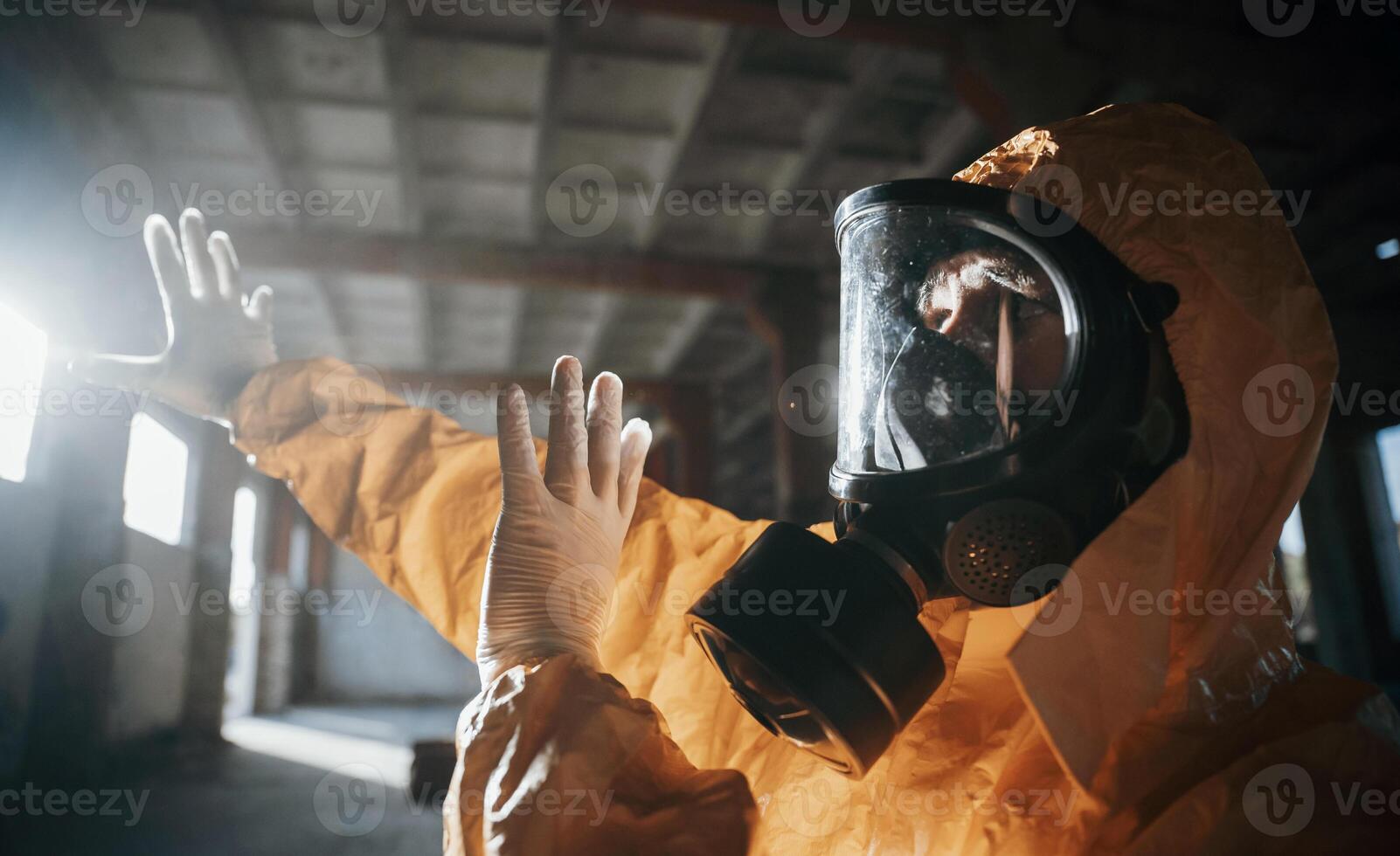 Light from nuclear explosion. .Man dressed in chemical protection suit in the ruins of the post apocalyptic building photo