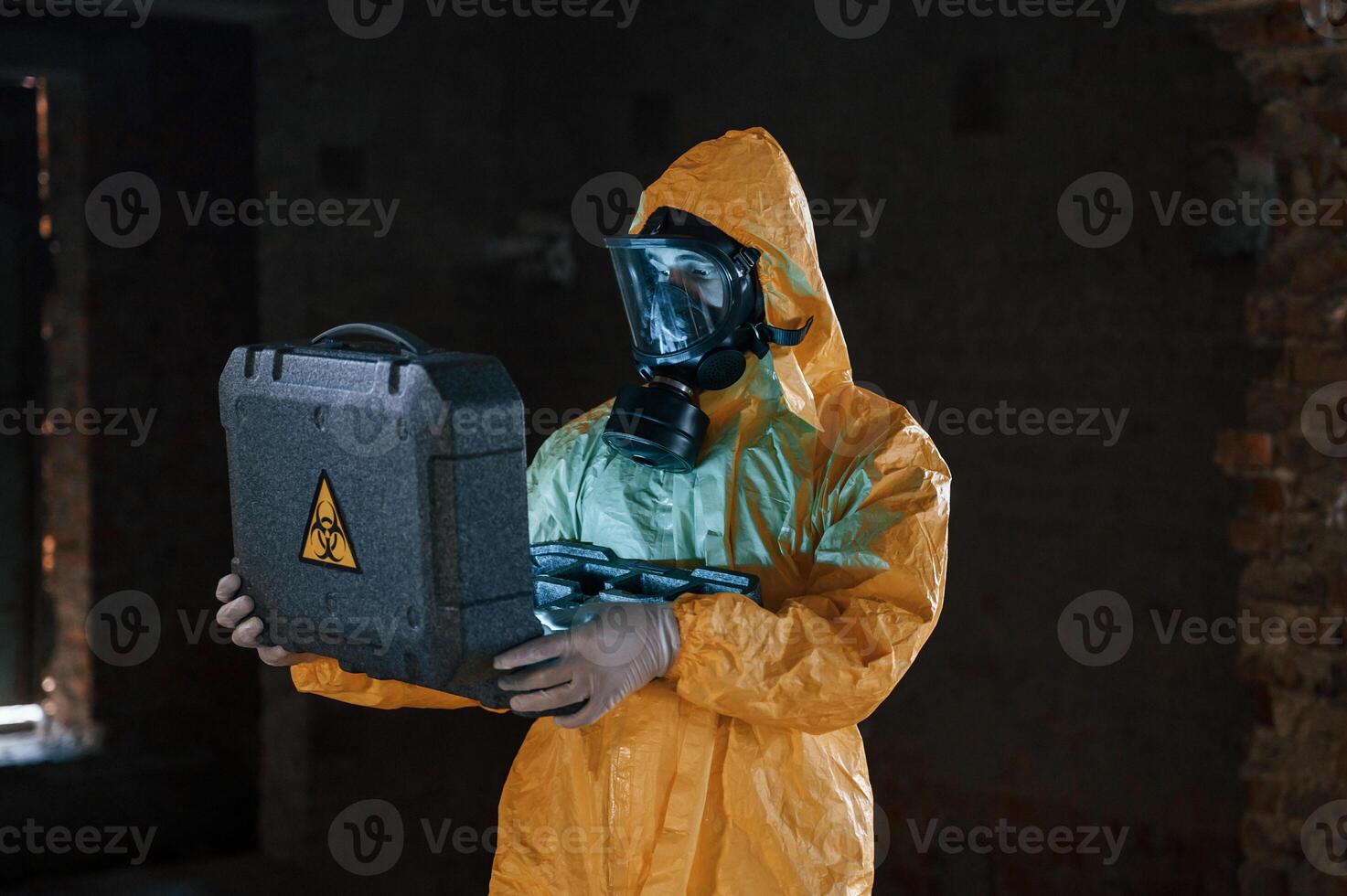 Frightened, scientist is with radioactive materials. Man dressed in chemical protection suit in the ruins of the post apocalyptic building photo