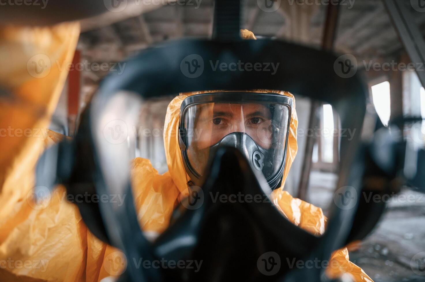 First person view through respirator. Man dressed in chemical protection suit in the ruins of the post apocalyptic building photo