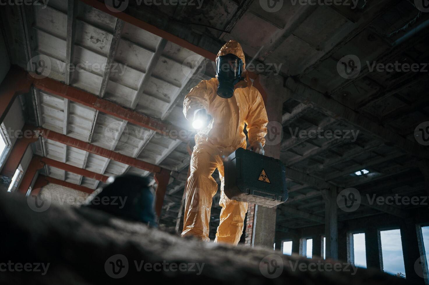 Looking below ,at the object. Man dressed in chemical protection suit in the ruins of the post apocalyptic building photo