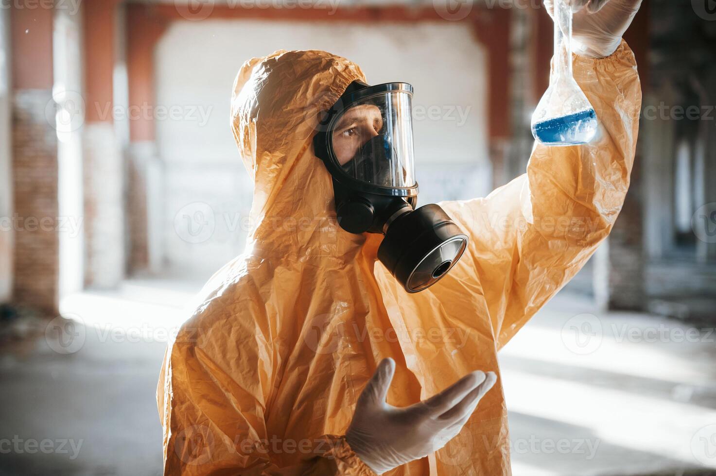 A test tube, with radioactive materials. Man dressed in chemical protection suit in the ruins of the post apocalyptic building photo