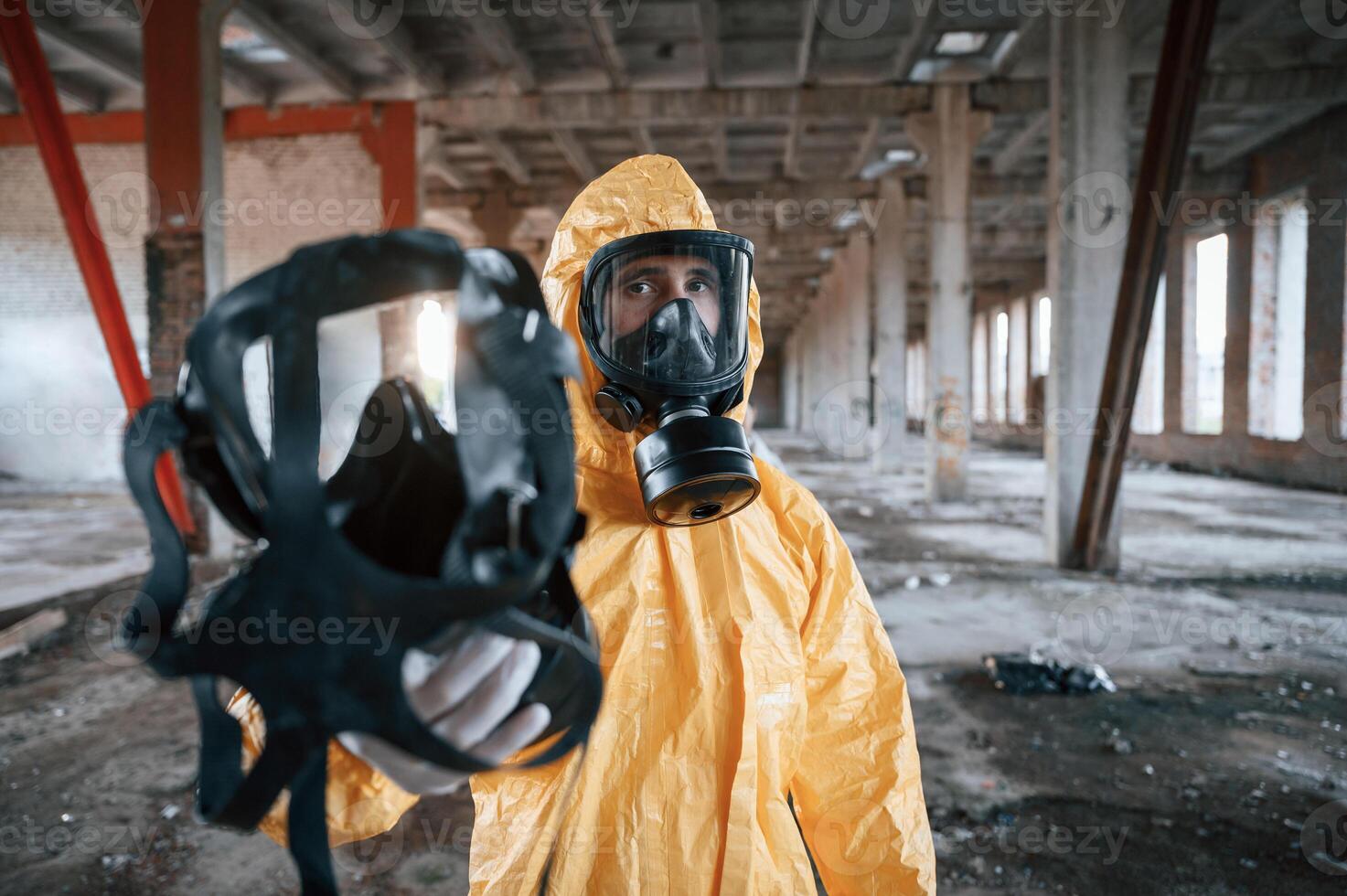 Giving the respirator. Man dressed in chemical protection suit in the ruins of the post apocalyptic building photo