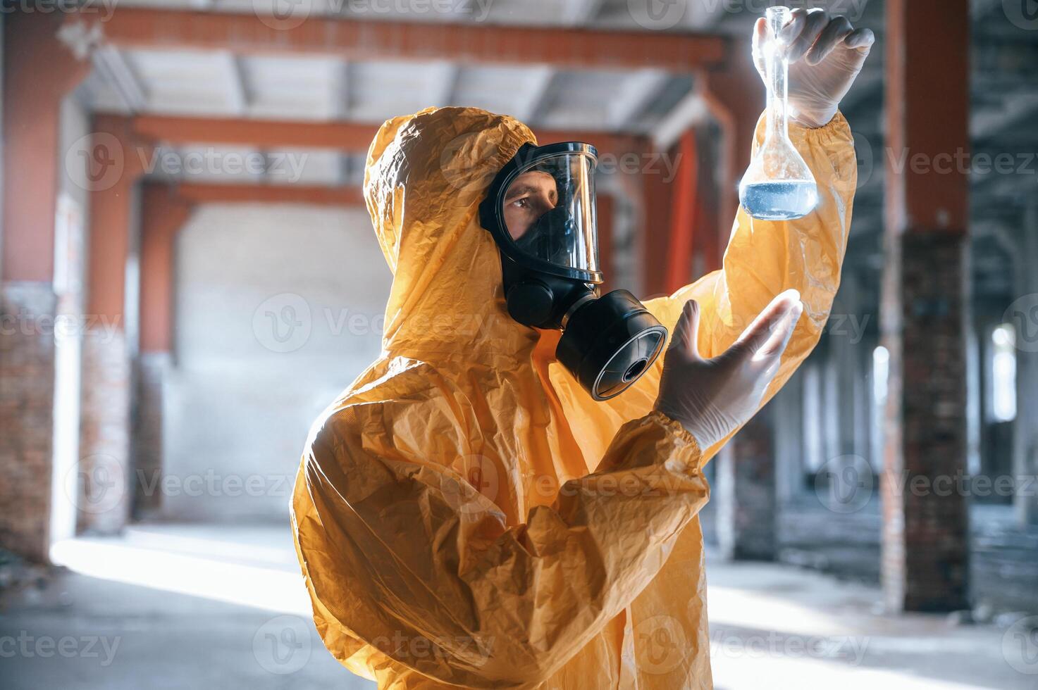A test tube with radioactive materials. Man ,dressed in chemical protection suit in the ruins of the post apocalyptic building photo