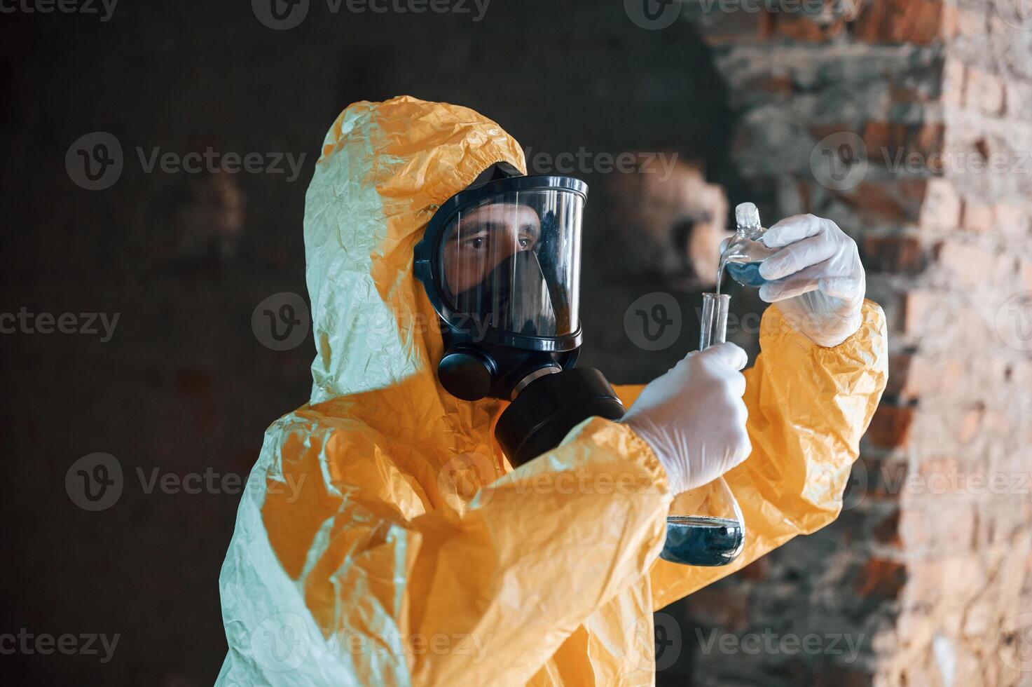 A test tube ,with radioactive materials. Man dressed in chemical protection suit in the ruins of the post apocalyptic building photo