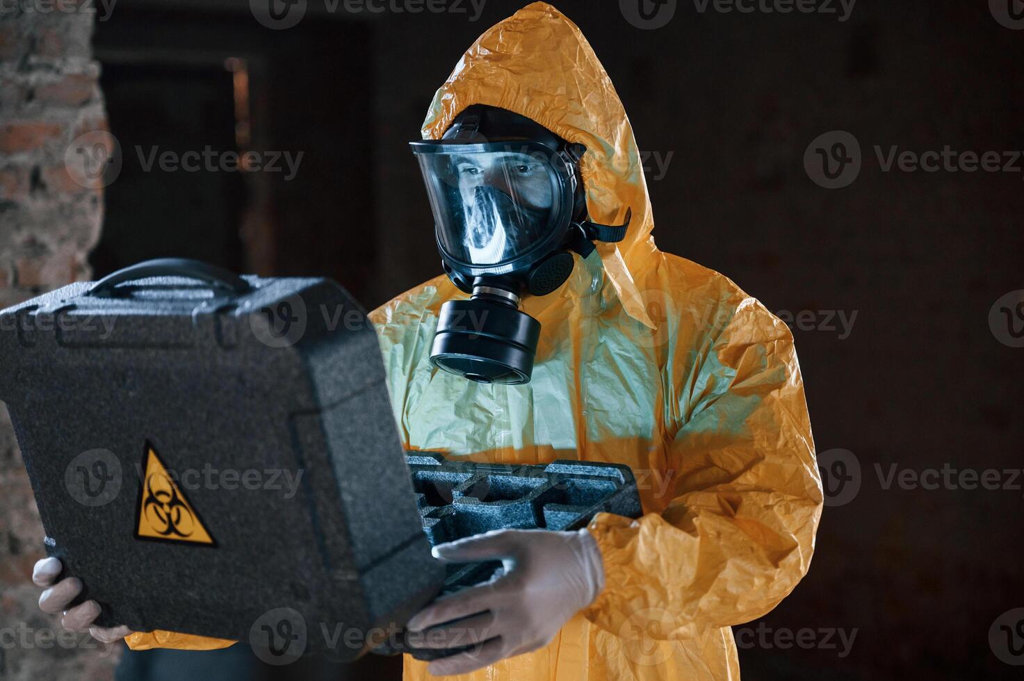 Frightened, scientist, is with radioactive materials. Man dressed in chemical protection suit in the ruins of the post apocalyptic building photo