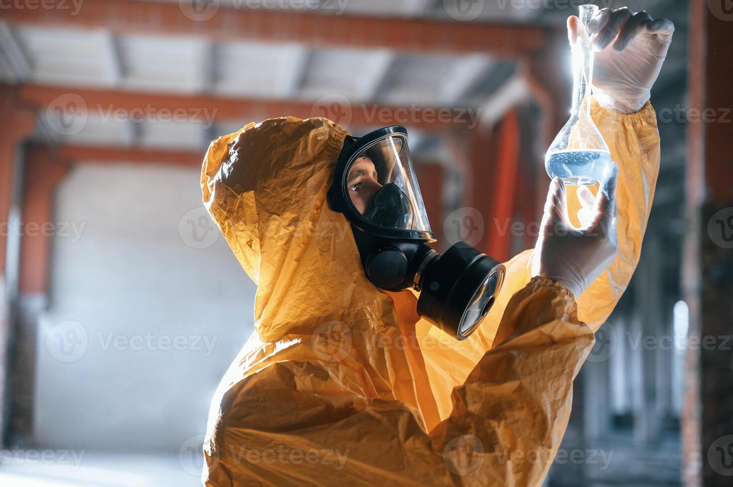 Examining radioactive liquid. Man dressed in chemical, protection suit in the ruins of the post apocalyptic building photo