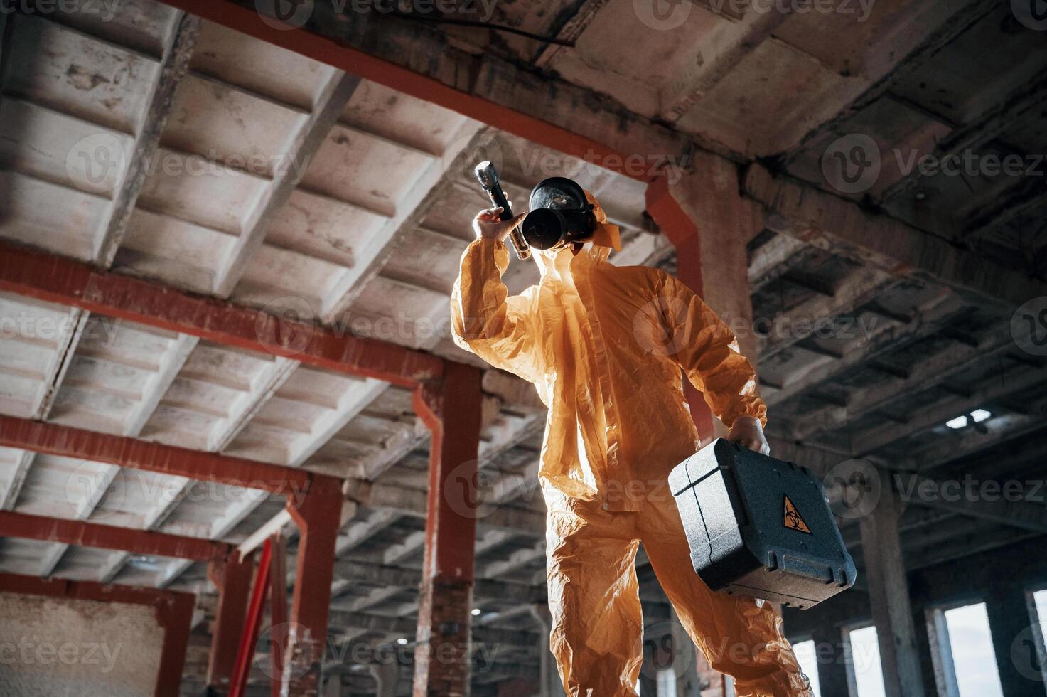 Bottom view. Man dressed in chemical protection suit, in the ruins of the post apocalyptic building photo