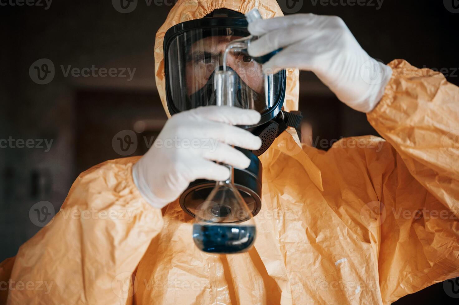 Holding a test tube and examining radioactive liquid.. Man dressed in chemical protection suit in the ruins of the post apocalyptic building photo