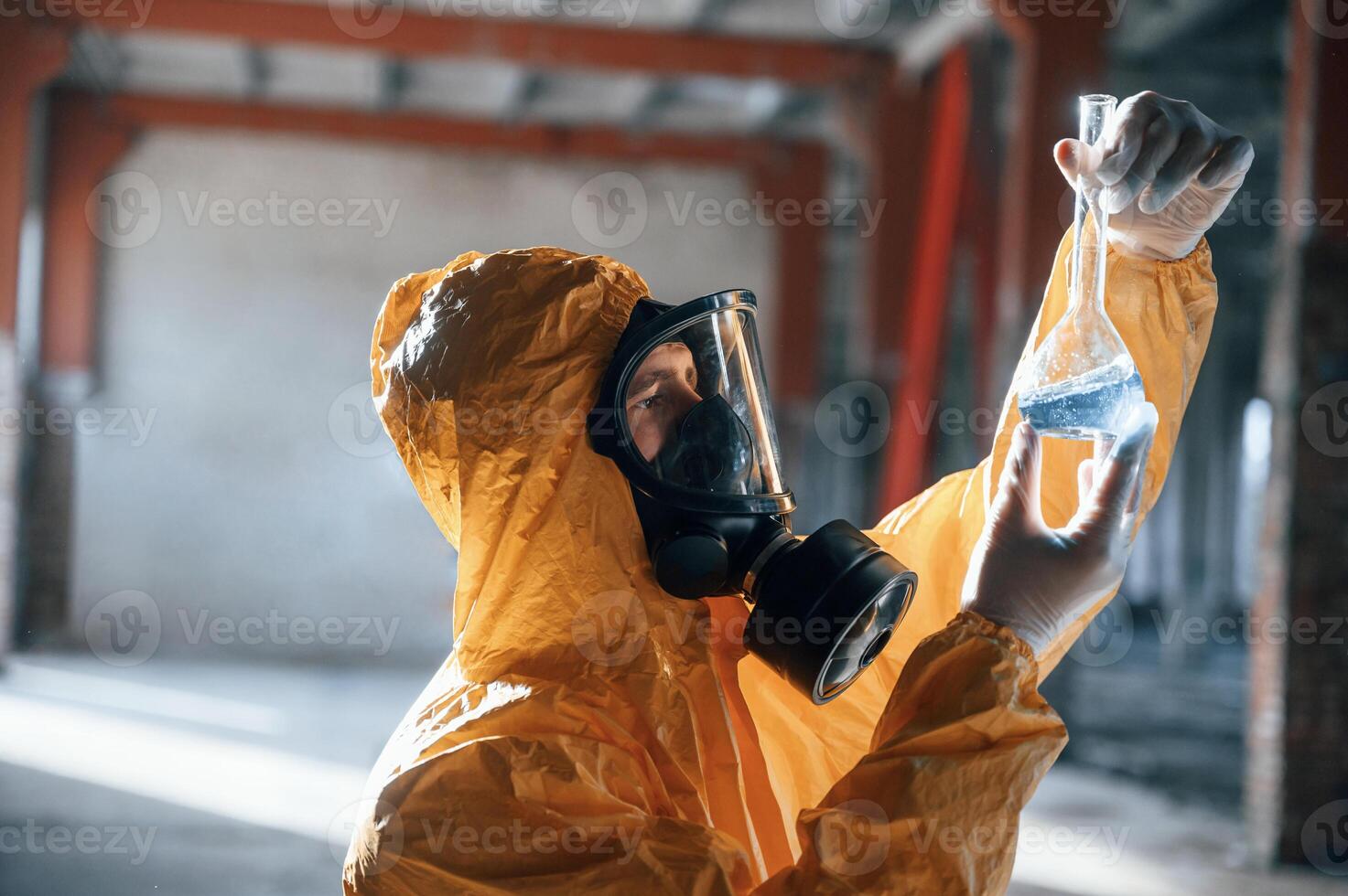 Examining radioactive liquid.. Man dressed in chemical protection suit in the ruins of the post apocalyptic building photo