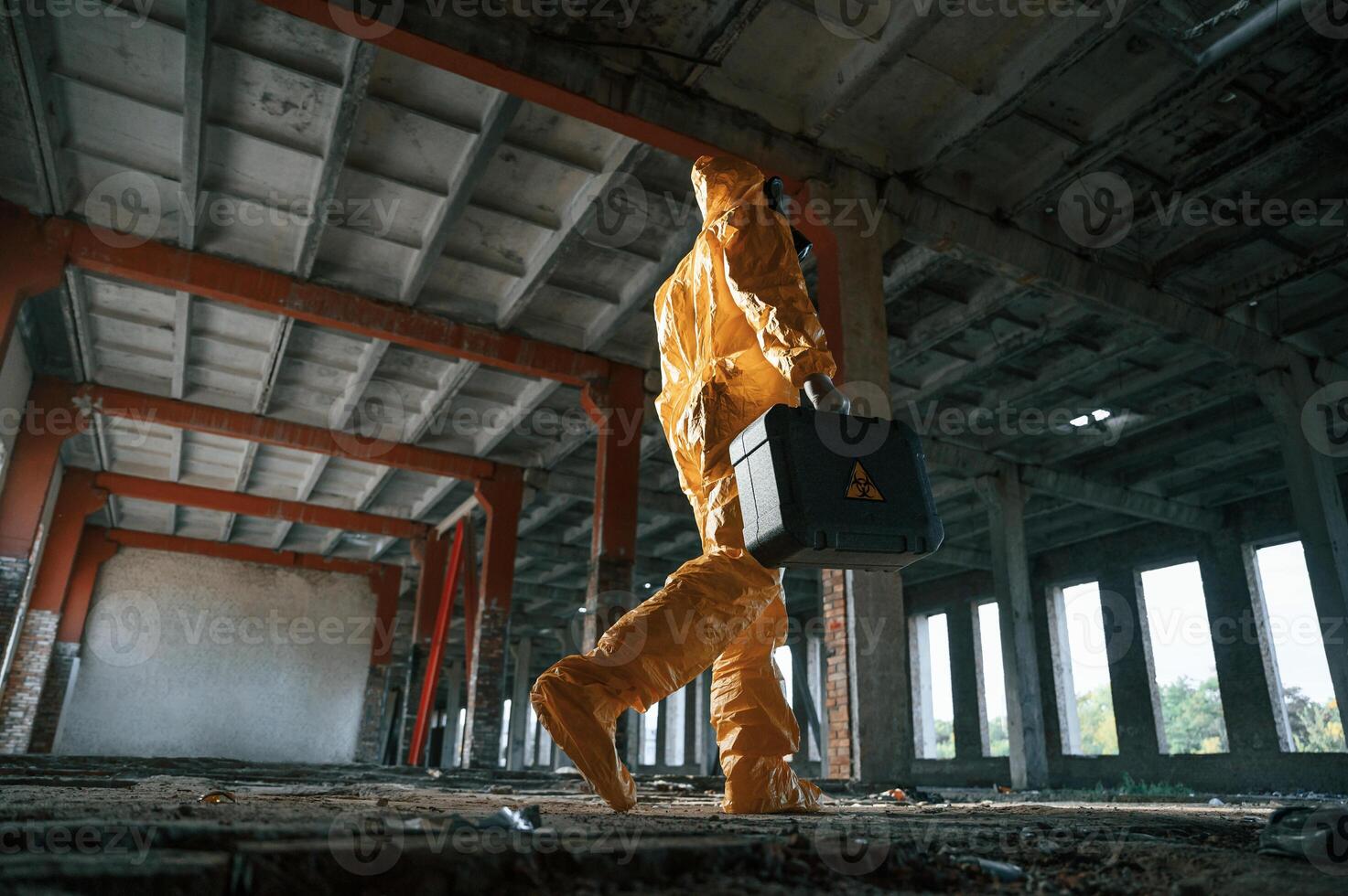 View, from below. Man dressed in chemical protection suit in the ruins of the post apocalyptic building photo