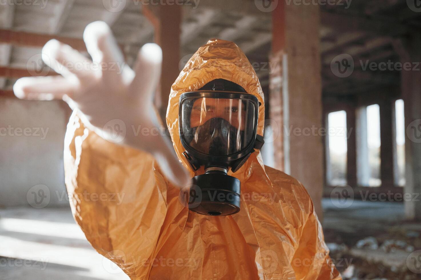 Man dressed in ,chemical protection suit in the ruins of the post apocalyptic building photo