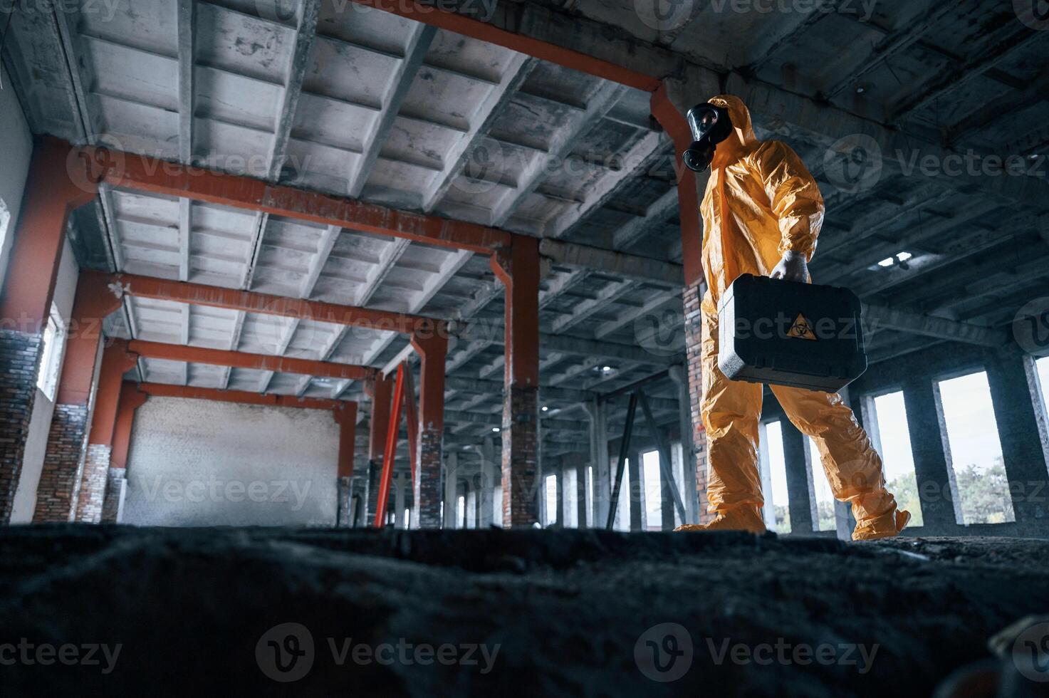 View from, below. Man dressed in chemical protection suit in the ruins of the post apocalyptic building photo