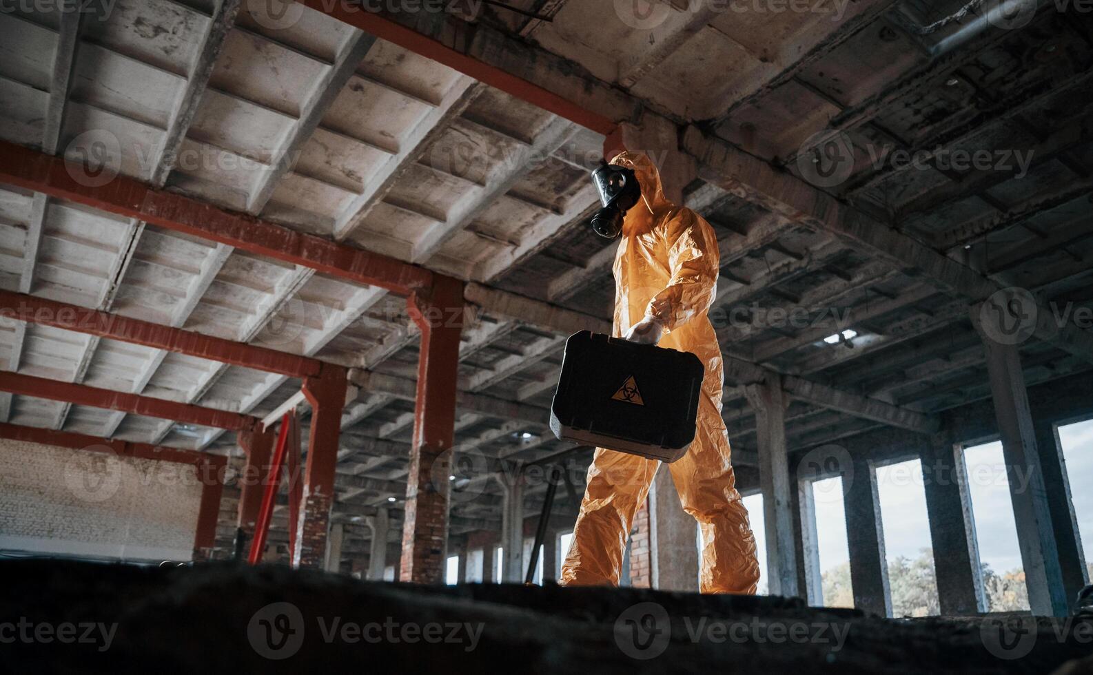 Bottom view. Man dressed in chemical ,,protection suit in the ruins of the post apocalyptic building photo