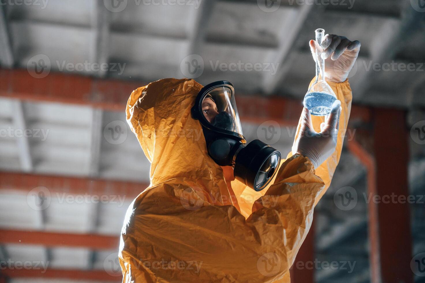Examining radioactive liquid. Man ,dressed in chemical protection suit in the ruins of the post apocalyptic building photo