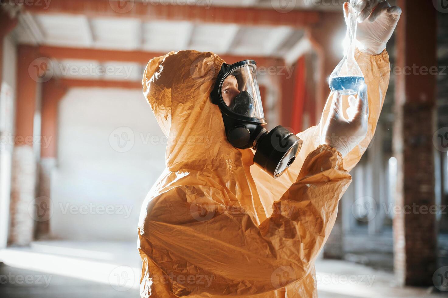 A, test ,tube with radioactive materials. Man dressed in chemical protection suit in the ruins of the post apocalyptic building photo