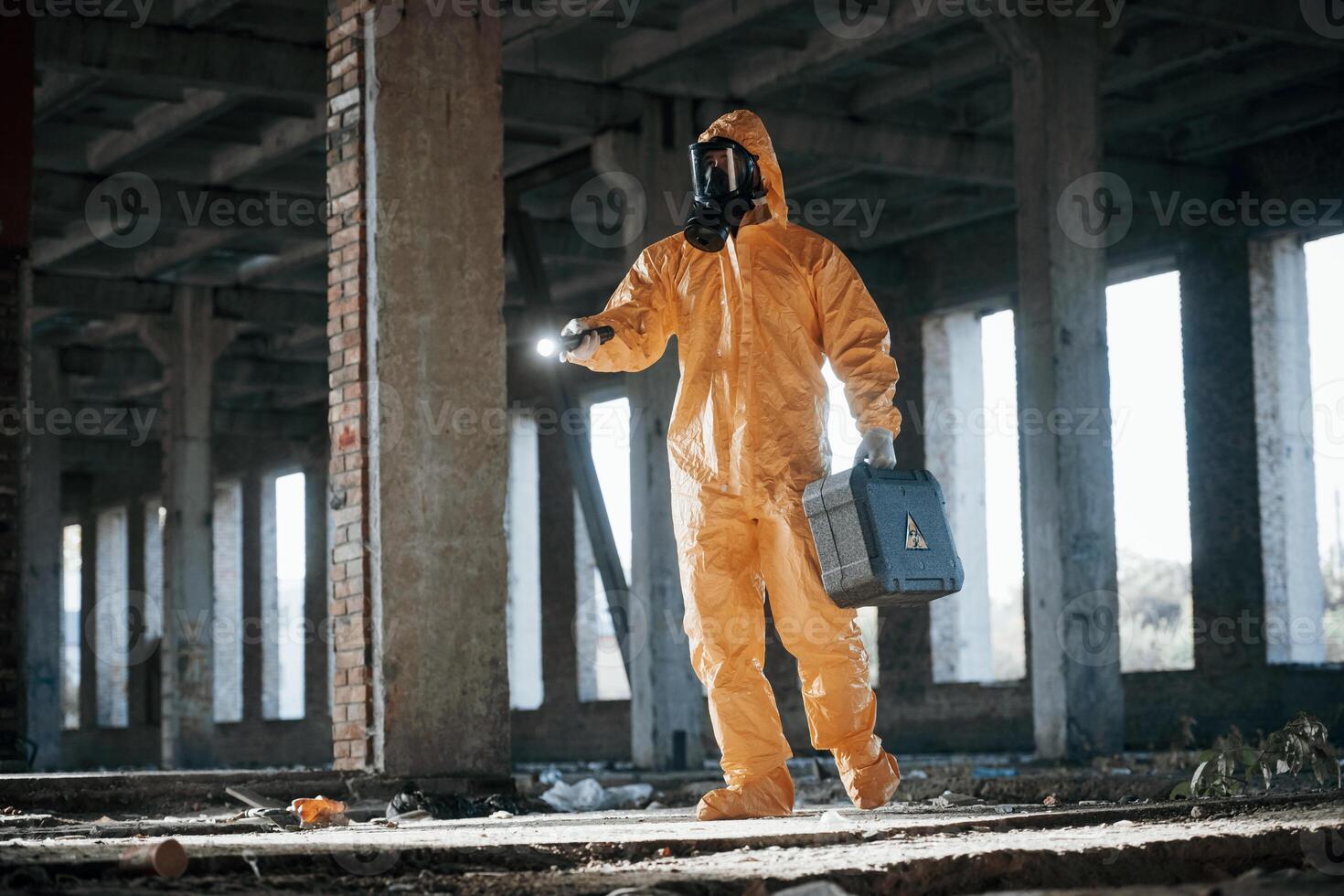 With flashlight. Man dressed in chemical protection ,suit in the ruins of the post apocalyptic building photo