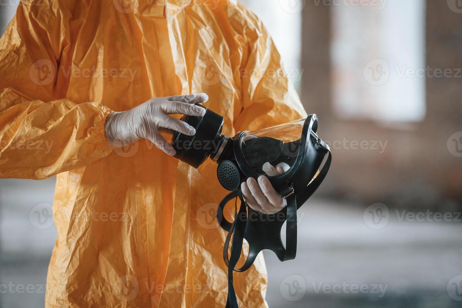 Holding a respirator. Man dressed in chemical protection .suit in the ruins of the post apocalyptic building photo