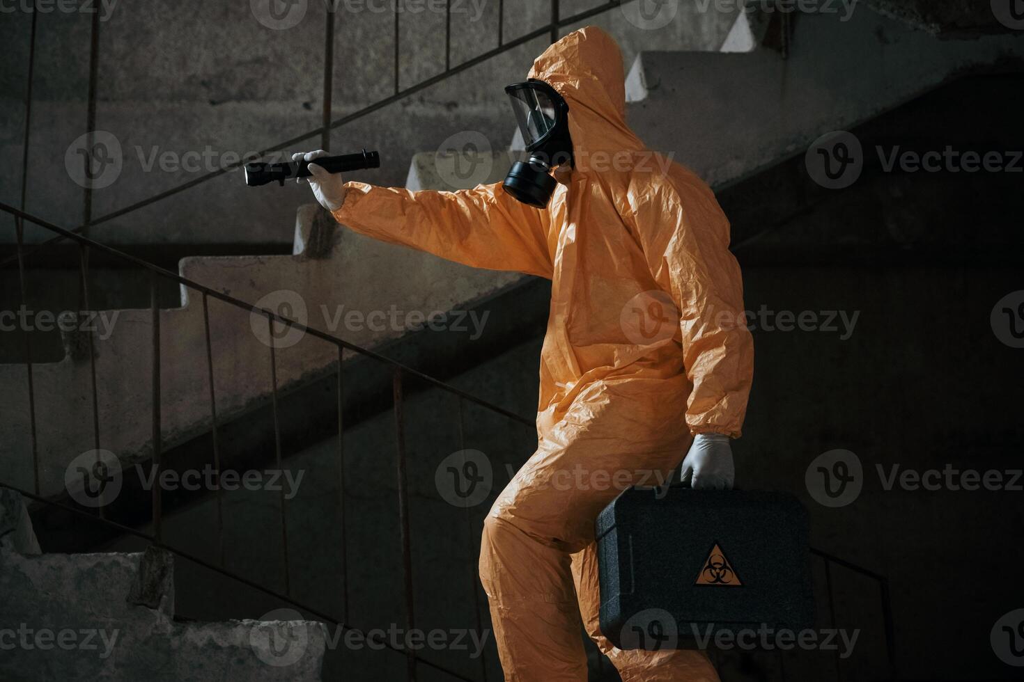 View from the side. Man, dressed, in chemical protection suit in the ruins of the post apocalyptic building photo