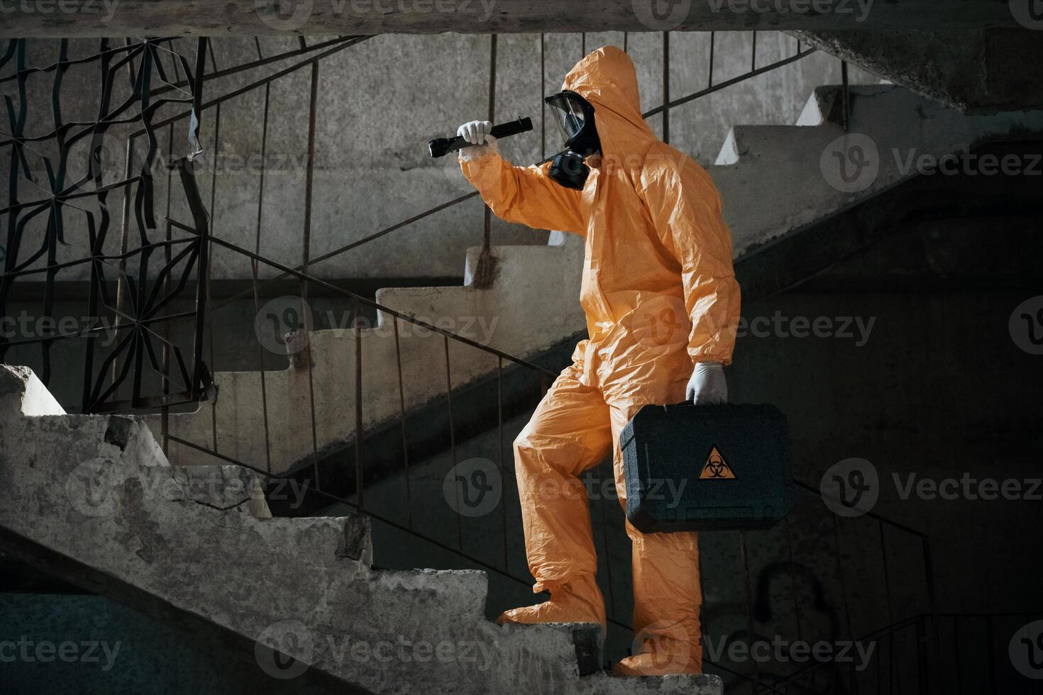 View from the ,side. Man dressed ,in chemical protection suit in the ruins of the post apocalyptic building photo