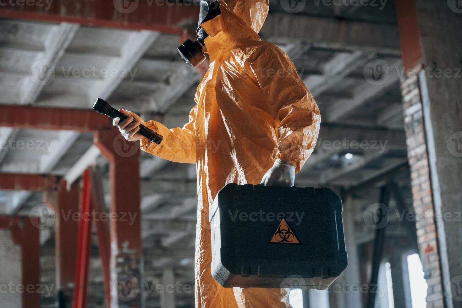 View from the side. Man dressed in chemical, protection suit in the ruins of the post apocalyptic building photo