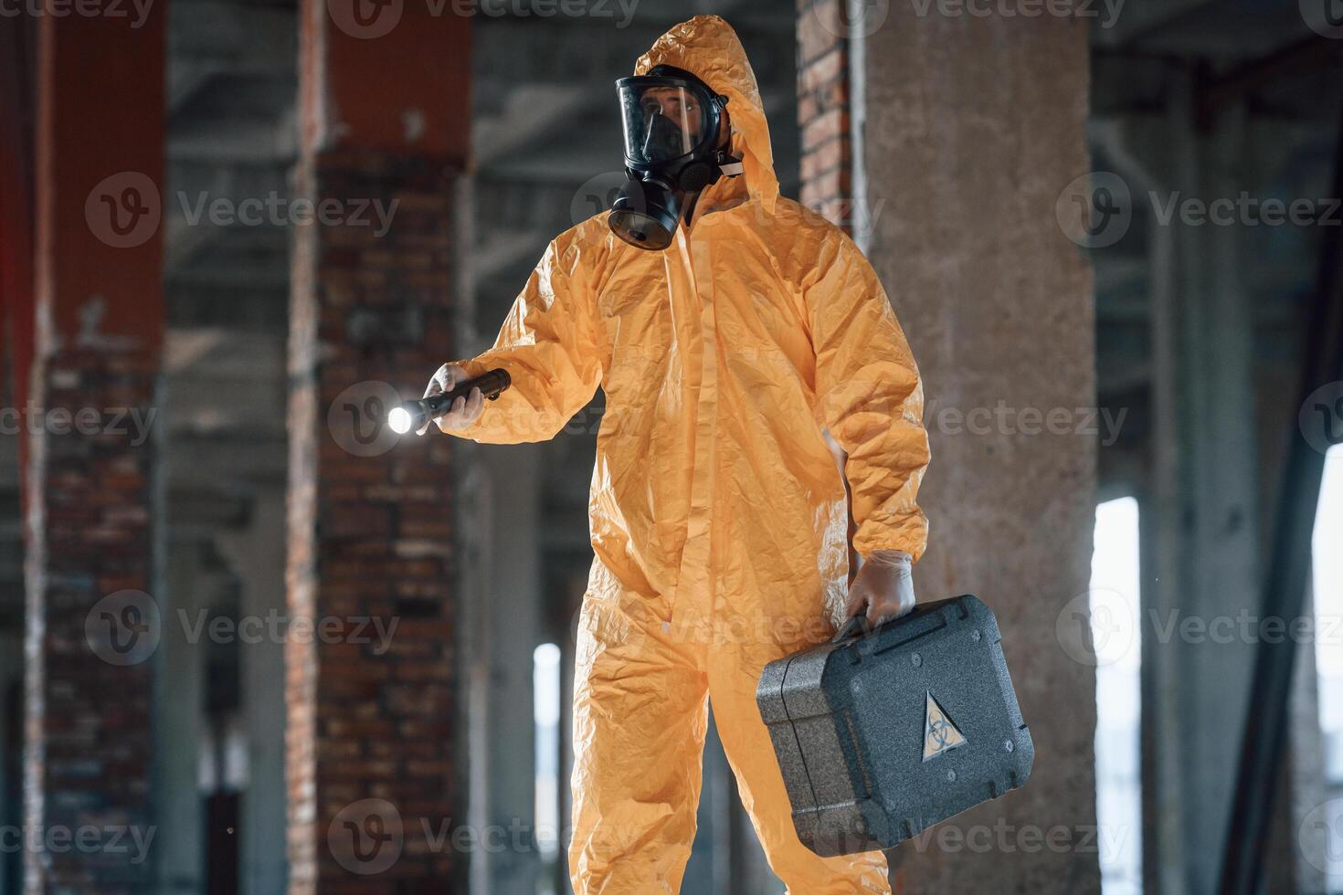 Man, dressed in ,chemical protection suit in the ruins of the post apocalyptic building photo