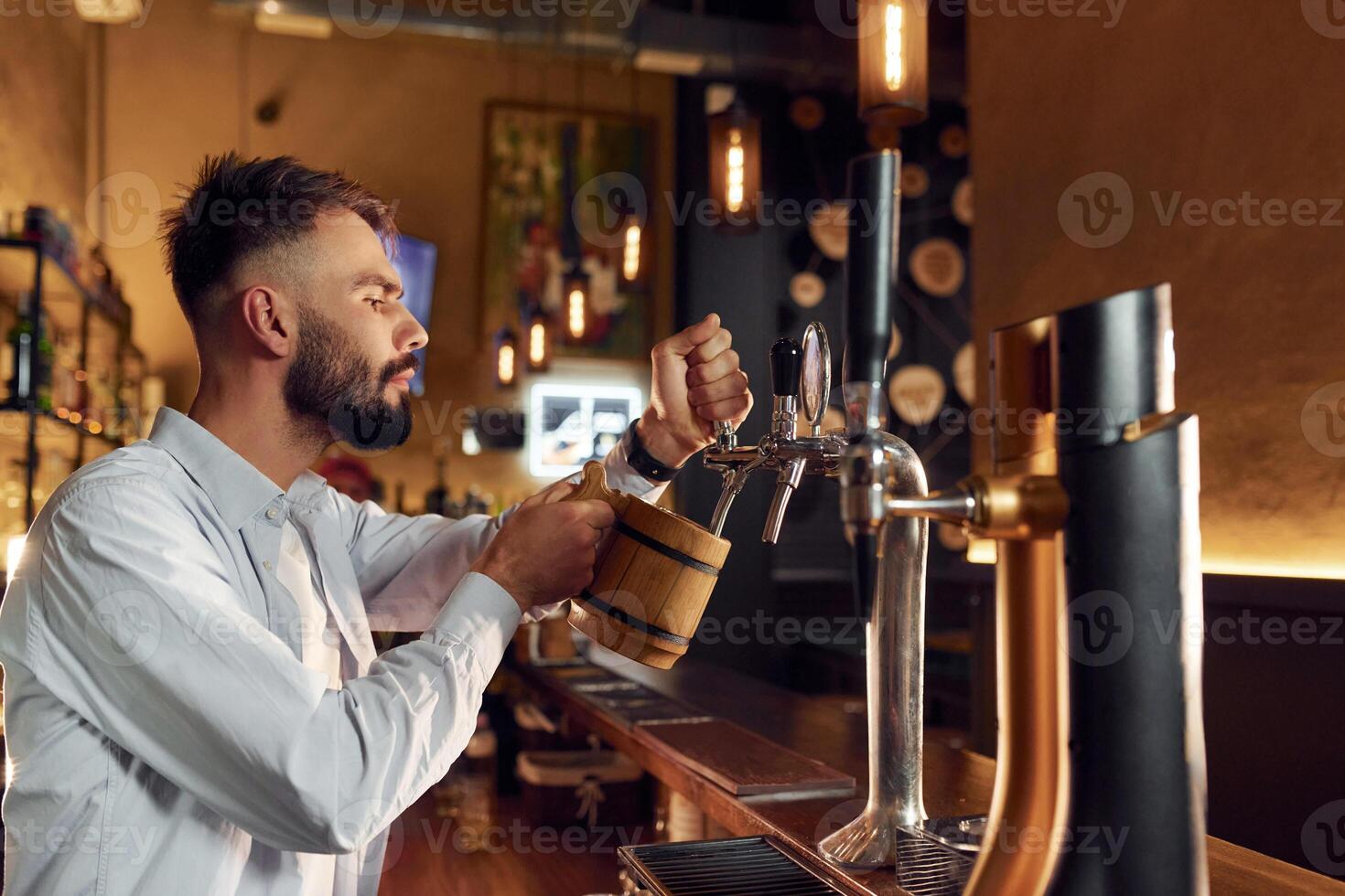 Side ,view. Bartender, pours beer. Man is working in the bar photo