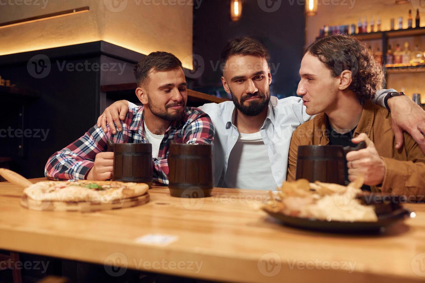 Having a conversation.. Three, friends are in the bar drinking beer and having a good time photo