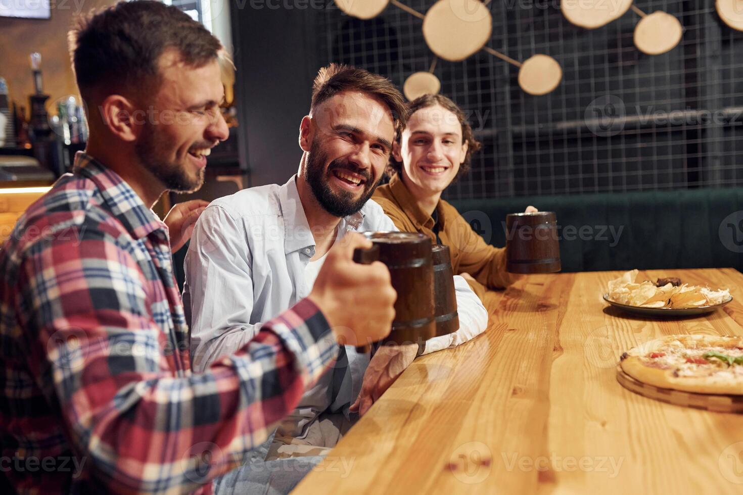 Sitting and smiling. Three ,friends are in the bar ,drinking beer and having a good time photo