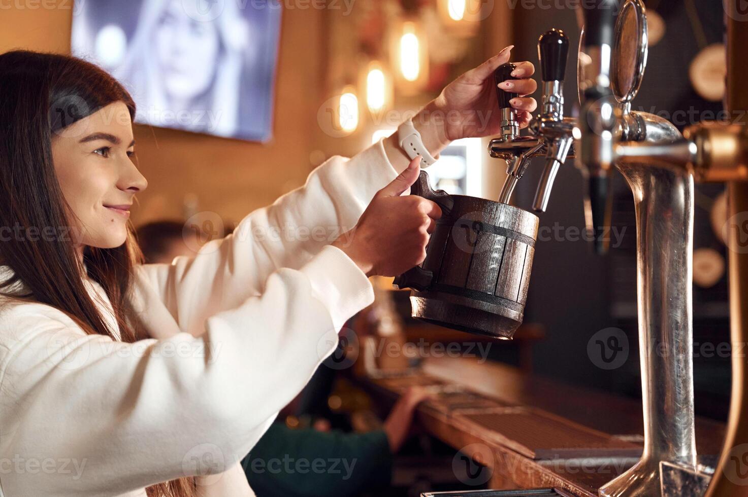 Bartender pours beer. Woman is working in the bar photo