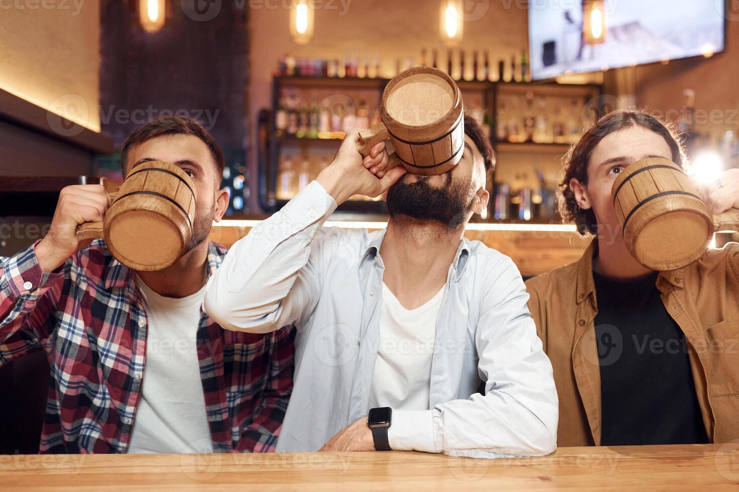Three friends are in the bar, drinking beer and ,having a good time photo