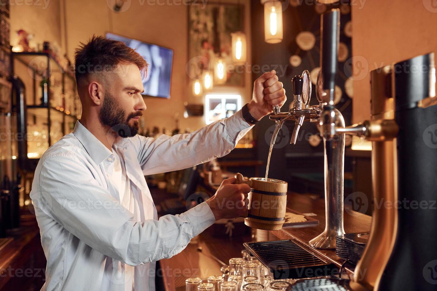 Bartender pours beer. Man is working in the bar. photo