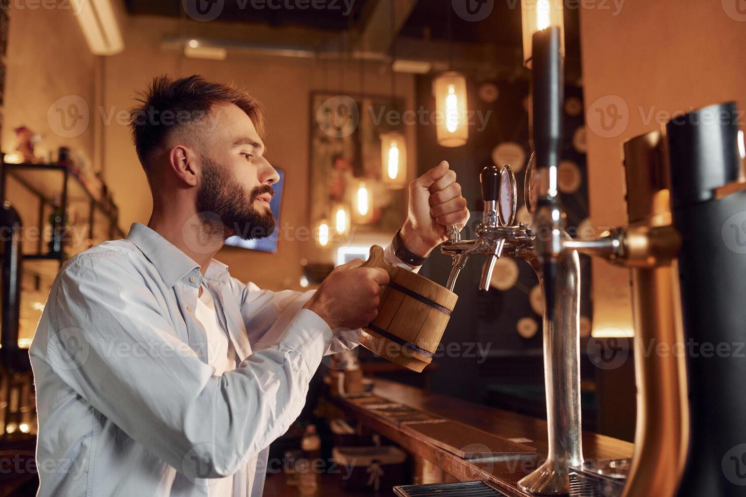 View from the side. Bartender pours beer. Man is working in the bar photo